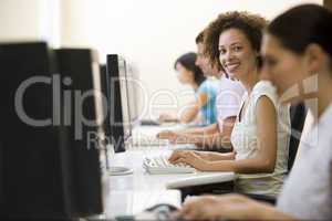 Four people in computer room typing and smiling
