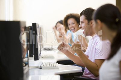 Four people in computer room cheering and smiling