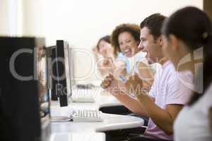 Four people in computer room cheering and smiling