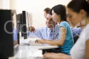 Man assisting woman in computer room smiling