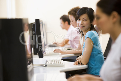 Four people sitting in computer room smiling