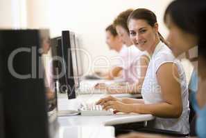 Four people sitting in computer room typing and smiling