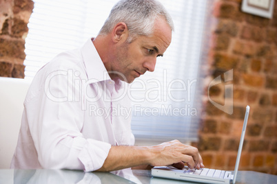 Businessman sitting in office typing on laptop