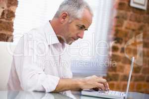 Businessman sitting in office typing on laptop