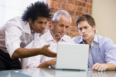 Three businessmen sitting in office with laptop