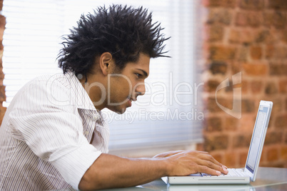 Businessman sitting in office typing on laptop