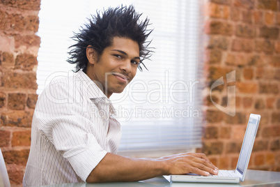 Businessman sitting in office typing on laptop