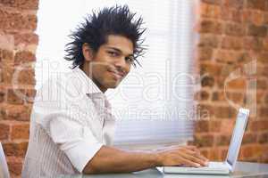 Businessman sitting in office typing on laptop