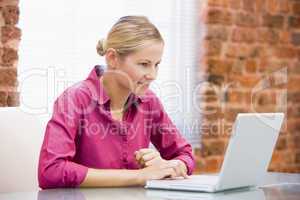 Businesswoman sitting in office using laptop smiling