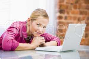 Businesswoman sitting in office with laptop smiling