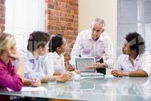 Five businesspeople in boardroom with laptop