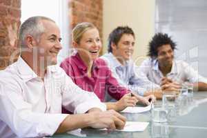 Four businesspeople in boardroom smiling