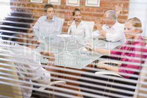 Five businesspeople in boardroom through window