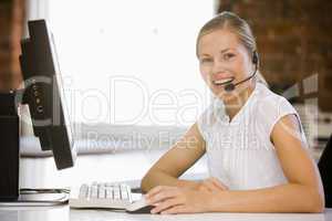 Businesswoman wearing headset sitting in office smiling
