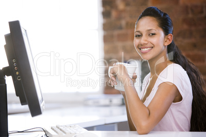 Businesswoman in office drinking coffee and smiling