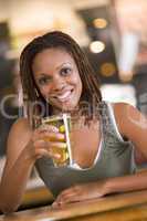 Eine dunkelhäutige Frau trinkt Bier