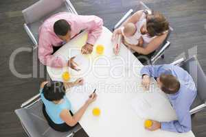 Four businesspeople in boardroom with one holding a baby