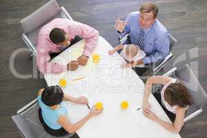 Four businesspeople in boardroom with one holding a baby