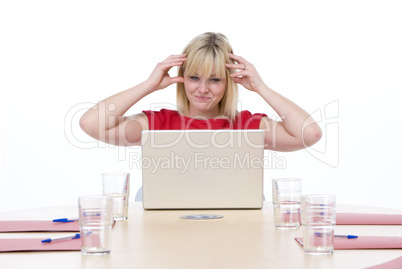 Businesswoman sitting in boardroom with laptop looking frustrate