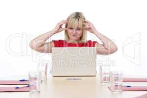 Businesswoman sitting in boardroom with laptop looking frustrate