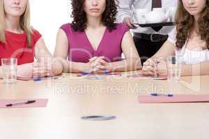 Three businesswomen sitting in boardroom being served coffee and