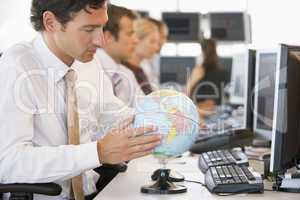 Businessman in office space with a desk globe