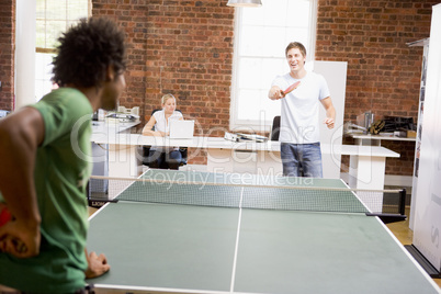 Two men in office space playing ping pong