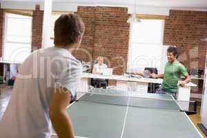 Two men in office space playing ping pong
