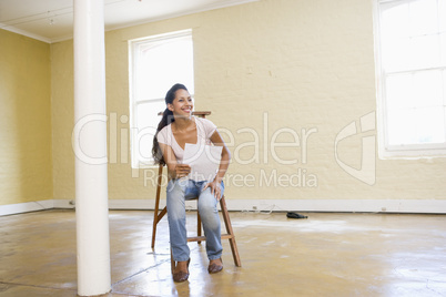 Woman sitting on ladder in empty space holding paper
