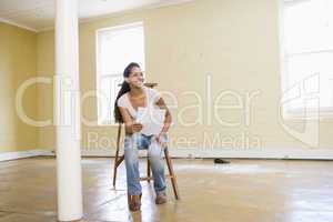Woman sitting on ladder in empty space holding paper
