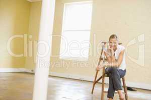 Woman sitting on ladder in empty space smiling