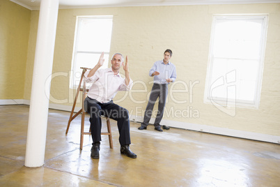 Two men with ladder in empty space making plans for room