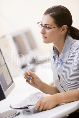 Woman in computer room circling items in a newspaper