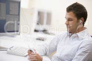 Man in computer room listening to MP3 player
