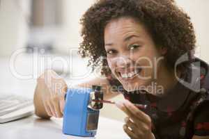 Woman in computer room using pencil sharpener and smiling