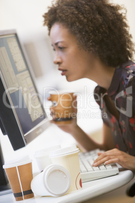 Woman in computer room with many cups of empty coffee around her