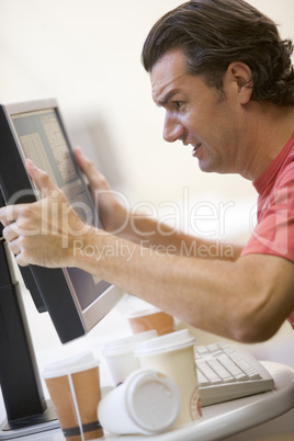 Man in computer room with many empty cups of coffee grabbing his