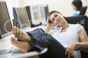 Woman in computer room with feet up thinking
