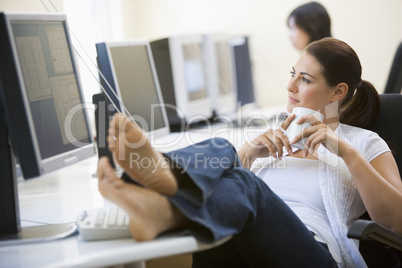 Woman in computer room with feet up drinking coffee