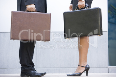 Two businesspeople holding briefcases outdoors