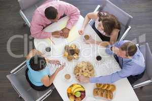 Four businesspeople at boardroom table with breakfast