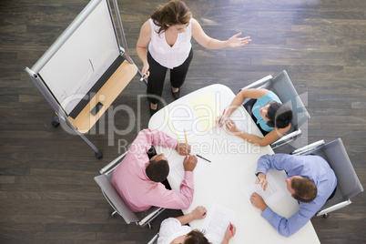 Four businesspeople at boardroom table watching presentation