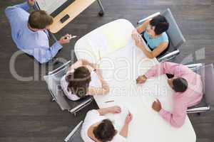 Four businesspeople at boardroom table watching presentation