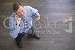 Businessman standing indoors using cellular phone and smiling