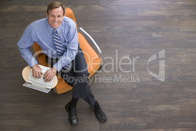 Businessman sitting indoors with laptop smiling