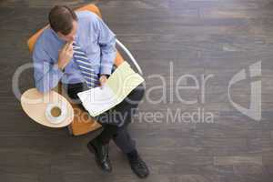 Businessman sitting indoors with coffee and folder