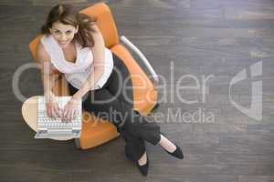 Businesswoman sitting indoors with laptop smiling