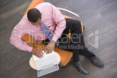 Businessman sitting indoors with laptop