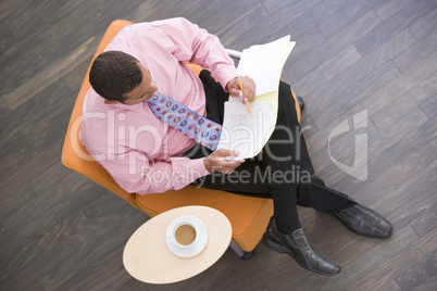 Businessman sitting indoors with coffee and folder