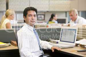 Businessman in cubicle with laptop